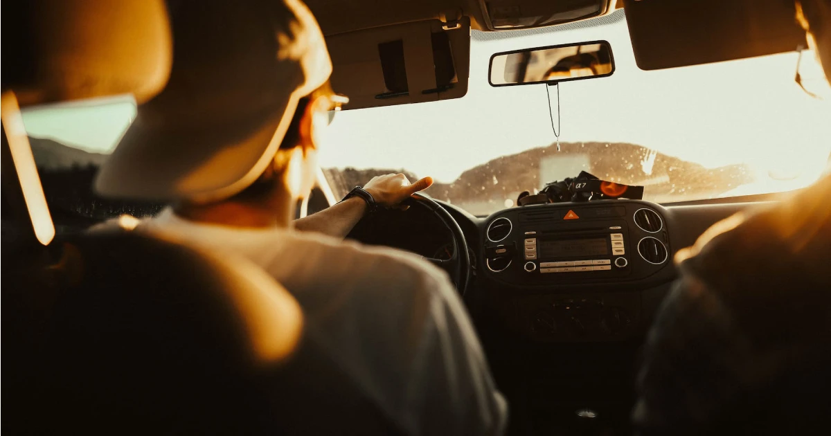 Jovem dirigindo um carro representando uma viajem e uma checklist de revisão automotiva para o carnaval